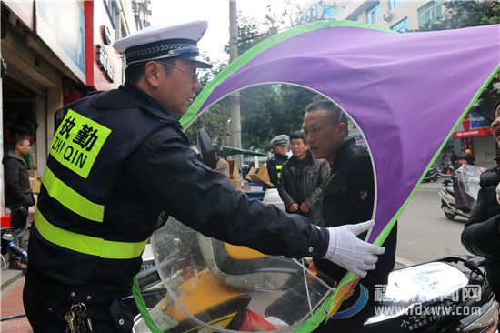 交警依法收繳部分市民在電動(dòng)車上違規(guī)安裝的遮雨蓋。.jpg