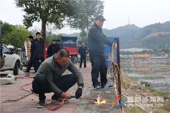 電焊工人在執(zhí)法人員的指導(dǎo)下，拆除人行道外的鐵柵欄，這些鐵柵欄為非法私建物品。.jpg